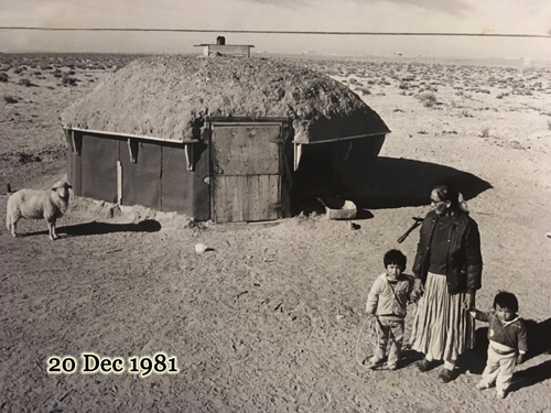 Mother and her daughter with a Navajo-Churro lamb at their hogan, 20 Dec 1981